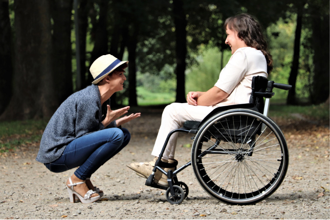A person squatting in front of another person in a wheelchair